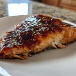 A close-up of a perfectly cooked salmon fillet topped with shiny Brown Sugar Teriyaki Salmon Glaze and sesame seeds.