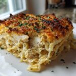 A generous slice of Cheesy Baked Chicken Alfredo with Crispy Top, showing creamy pasta, chicken, and a golden-brown crust.