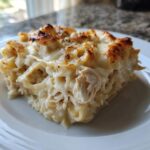 A close-up serving of Cheesy Chicken Alfredo Bake with Mozzarella showing shredded chicken and pasta covered in creamy sauce.