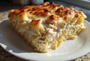 A generous slice of Cheesy Chicken Alfredo Bake with Mozzarella featuring creamy sauce and golden-brown topping.