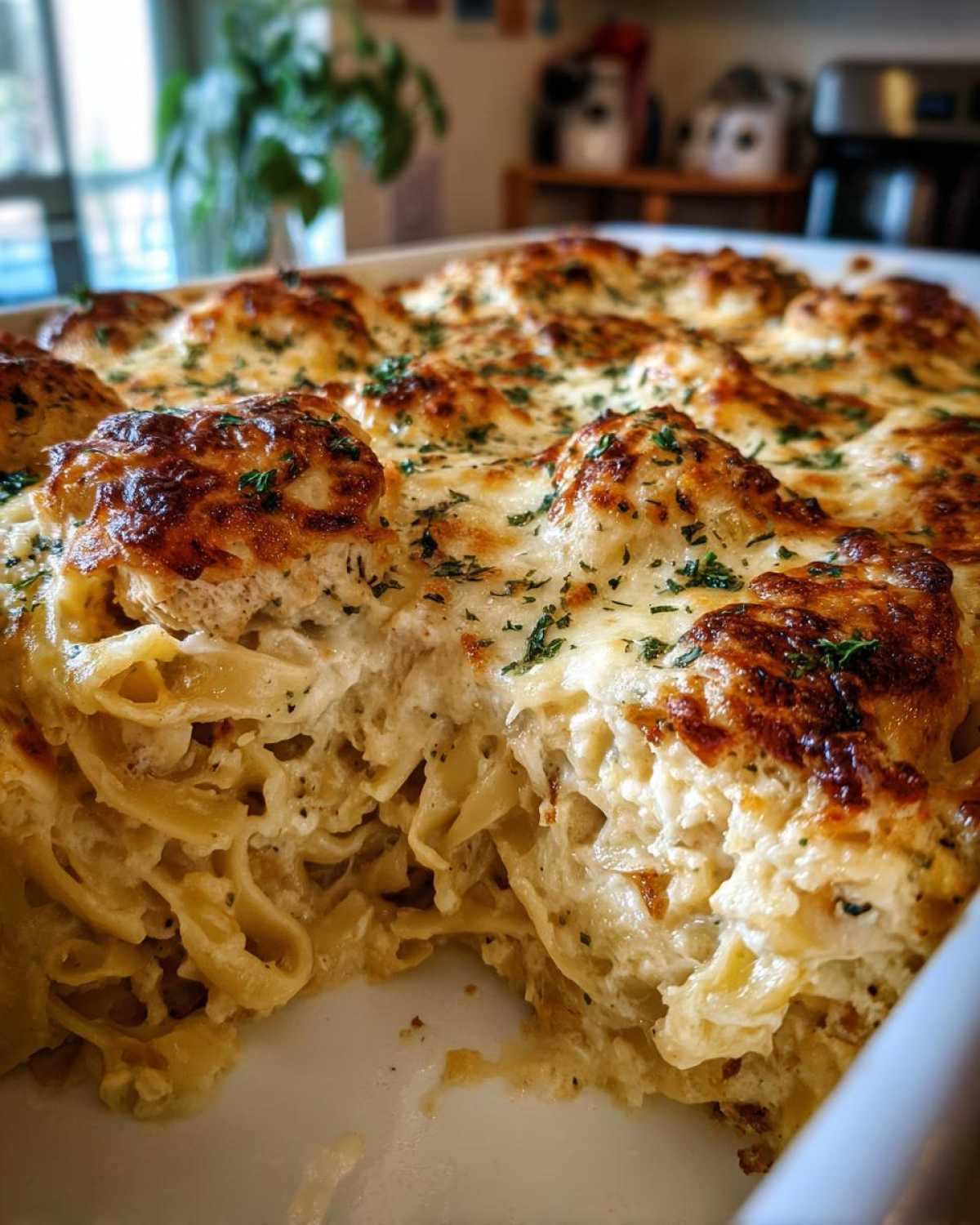 Close-up of a scoop taken out of the Cheesy Chicken Alfredo Bake showing creamy pasta and browned cheese topping.