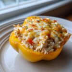 A single, bright yellow Cheesy Chicken and Rice Stuffed Pepper topped with melted, browned cheese and parsley.