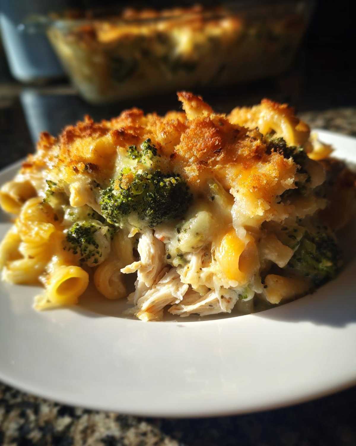 A close-up serving of Cheesy Chicken and Broccoli Pasta Bake with a golden, crispy topping.