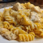 A close-up view of rotini pasta coated in a rich, creamy sauce with chunks of chicken, making up the Cheesy Chicken Pasta with Creamy Sauce.
