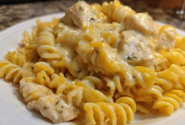 A close-up view of rotini pasta coated in a rich, creamy sauce with chunks of chicken, making up the Cheesy Chicken Pasta with Creamy Sauce.