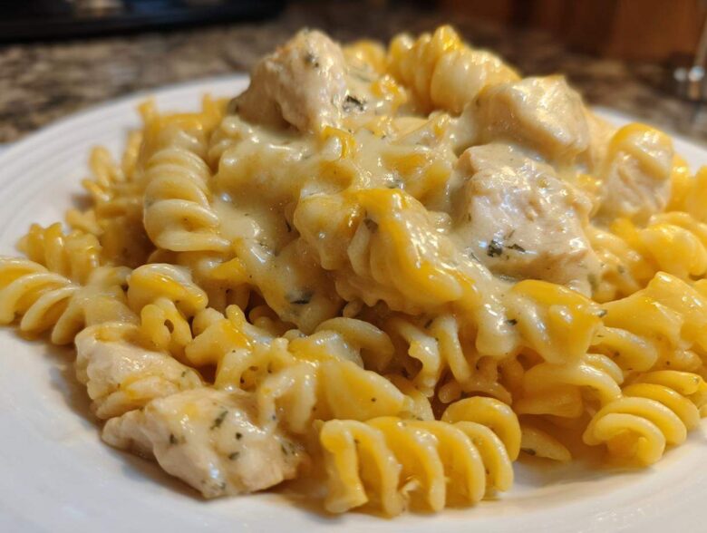 A close-up view of rotini pasta coated in a rich, creamy sauce with chunks of chicken, making up the Cheesy Chicken Pasta with Creamy Sauce.