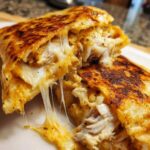 Close-up of a Cheesy Chicken Quesadilla cut in half showing melted, stretching cheese and shredded chicken filling.