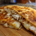 Close-up of a Cheesy Chicken Quesadilla with Crispy Tortilla, showing melted cheese stretching between shredded chicken filling.