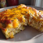 A close-up of a serving of Cheesy Chicken Tortilla Bake Easy Dinner, showing shredded chicken filling and a bubbly, melted cheddar cheese top.