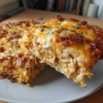 A close-up view of a serving being lifted from a Cheesy Chicken Tortilla Bake, showing shredded chicken and melted cheese topping.