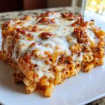 A close-up of a square serving of Cheesy Ground Beef Pasta Bake Comfort Food topped with melted mozzarella.