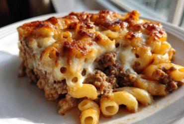 A close-up serving of Cheesy Ground Beef Pasta Bake showing browned cheese and creamy sauce over macaroni and ground beef.