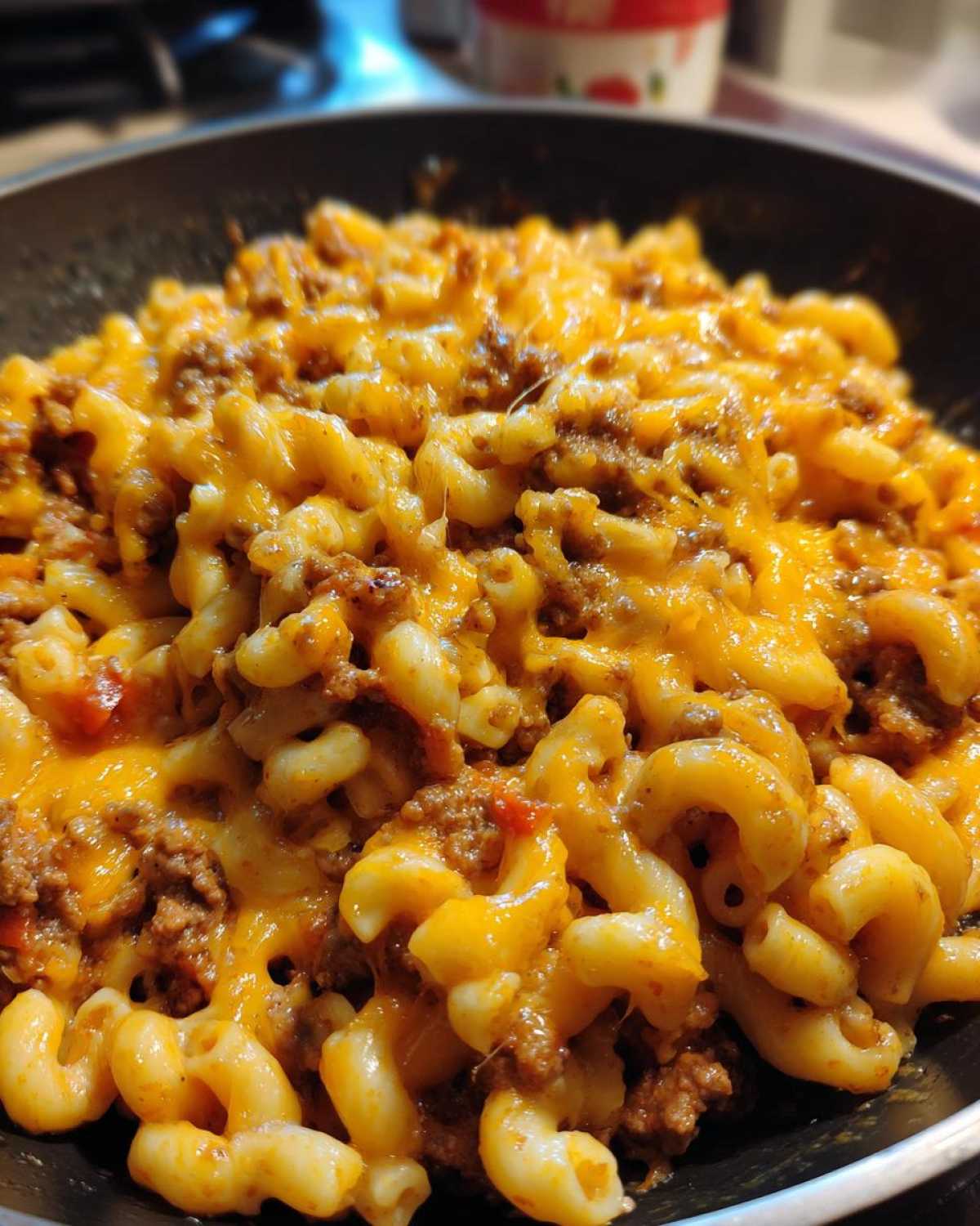 Close-up of Cheesy Ground Beef Pasta Skillet Comfort Food with melted cheddar topping over elbow macaroni and meat sauce.