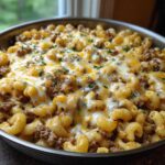 Close-up of a Cheesy Ground Beef Pasta Skillet in a pan, topped with melted white and cheddar cheese and parsley.