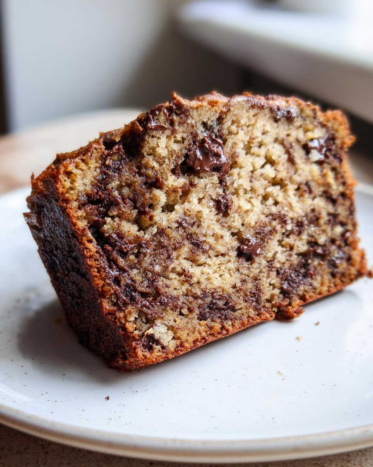 Close-up of a thick slice of The Chocolate Chip Banana Bread So Moist! showing a tender crumb and melted chocolate chips.