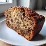Close-up of a moist slice of chocolate chip banana bread showing rich texture and melted chocolate chips.