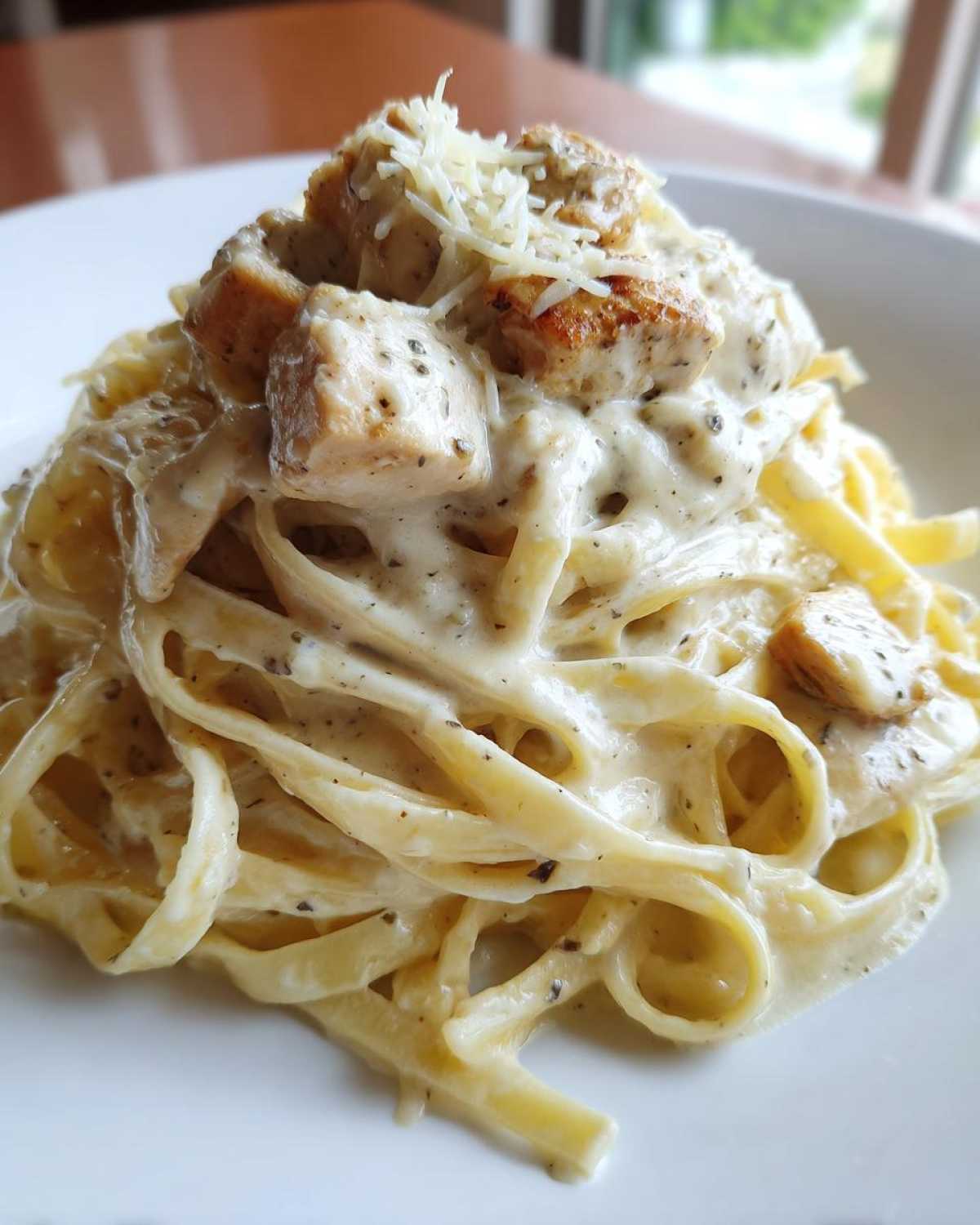 Close-up of fettuccine pasta coated in rich sauce with seasoned chicken pieces for Creamy Alfredo Chicken Pasta Easy Recipe.