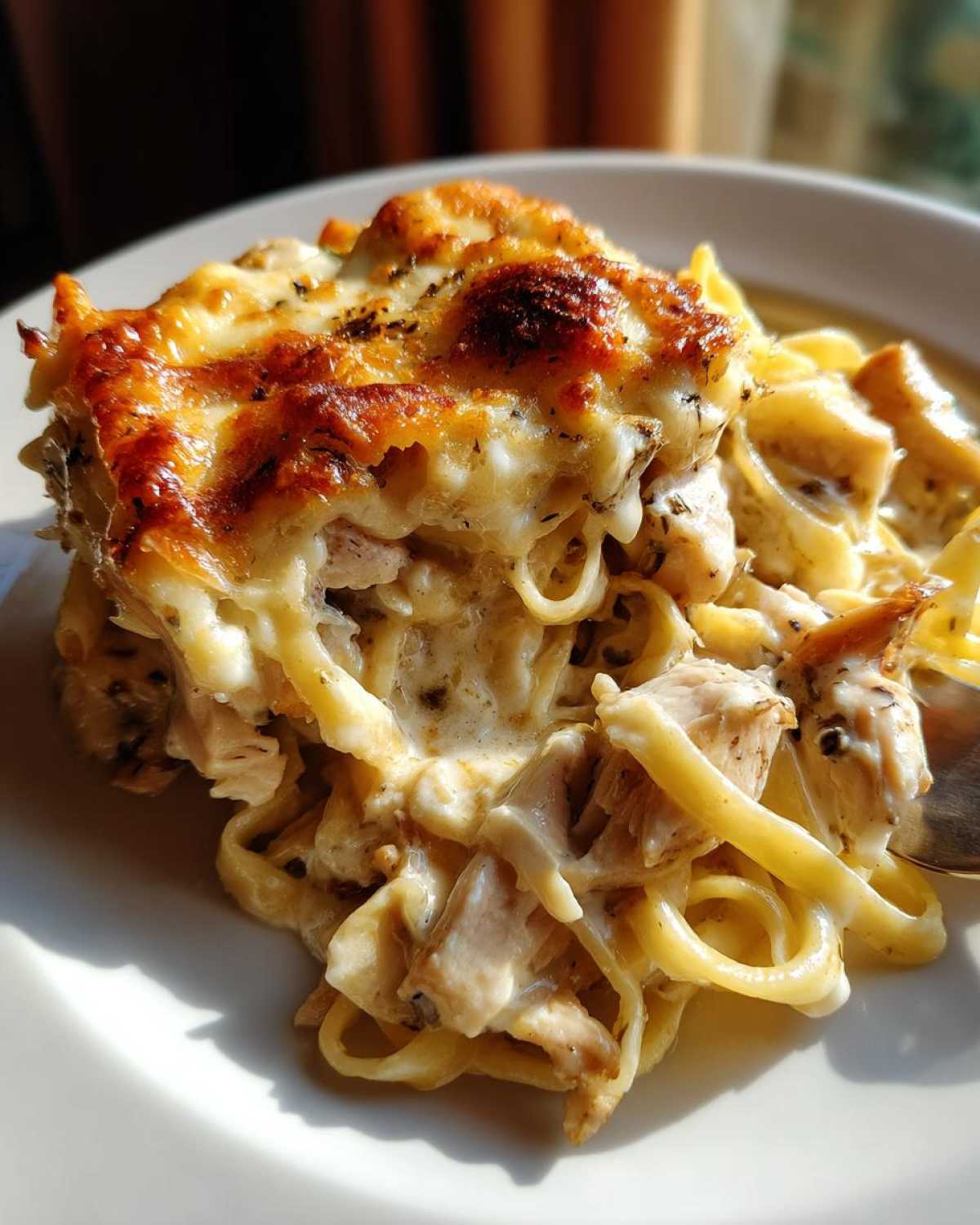 A close-up of a serving of Creamy Cajun Chicken Alfredo Bake with golden melted cheese topping.