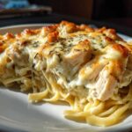 Close-up of a serving of Creamy Cajun Chicken Alfredo Bake with melted cheese and herbs.