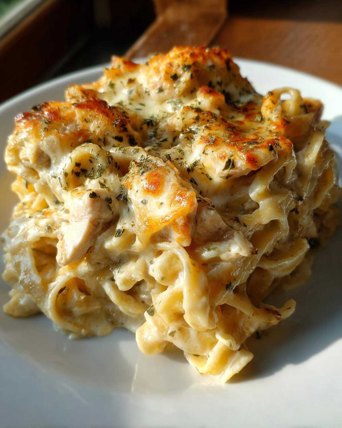 A close-up of a serving of Creamy Cajun Chicken Alfredo Bake with golden-brown melted cheese topping.