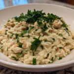 A close-up of creamy Garlic Parmesan Orzo with Chicken, topped generously with fresh chopped parsley in a white bowl.