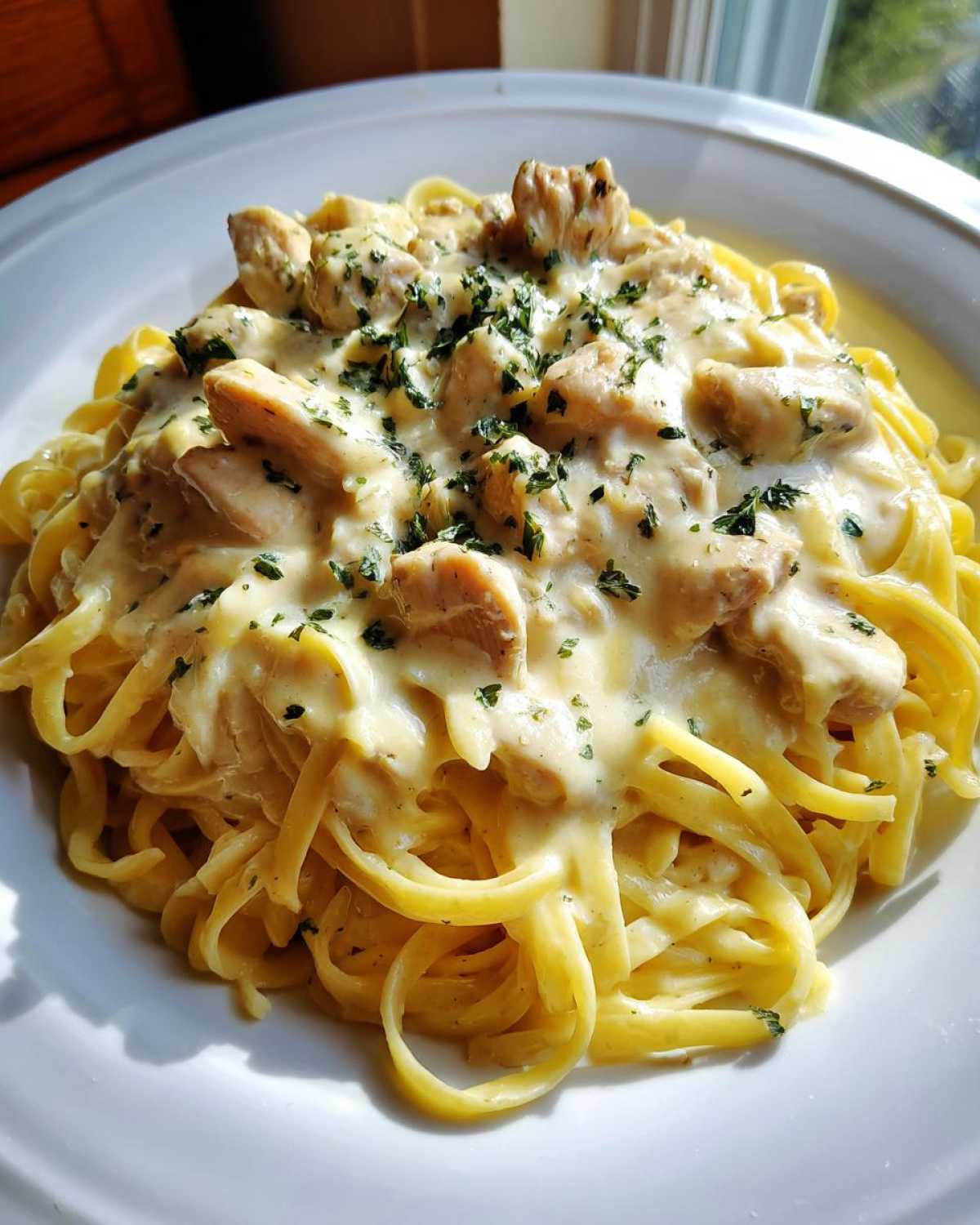 A close-up of a serving of Creamy Lemon Garlic Pasta with Chicken, topped with parsley.