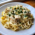 A close-up of Creamy Lemon Garlic Pasta with Chicken served on a white plate, topped with fresh parsley.