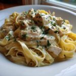 A close-up of creamy lemon garlic pasta with chicken pieces tossed in a rich white sauce and garnished with fresh parsley.