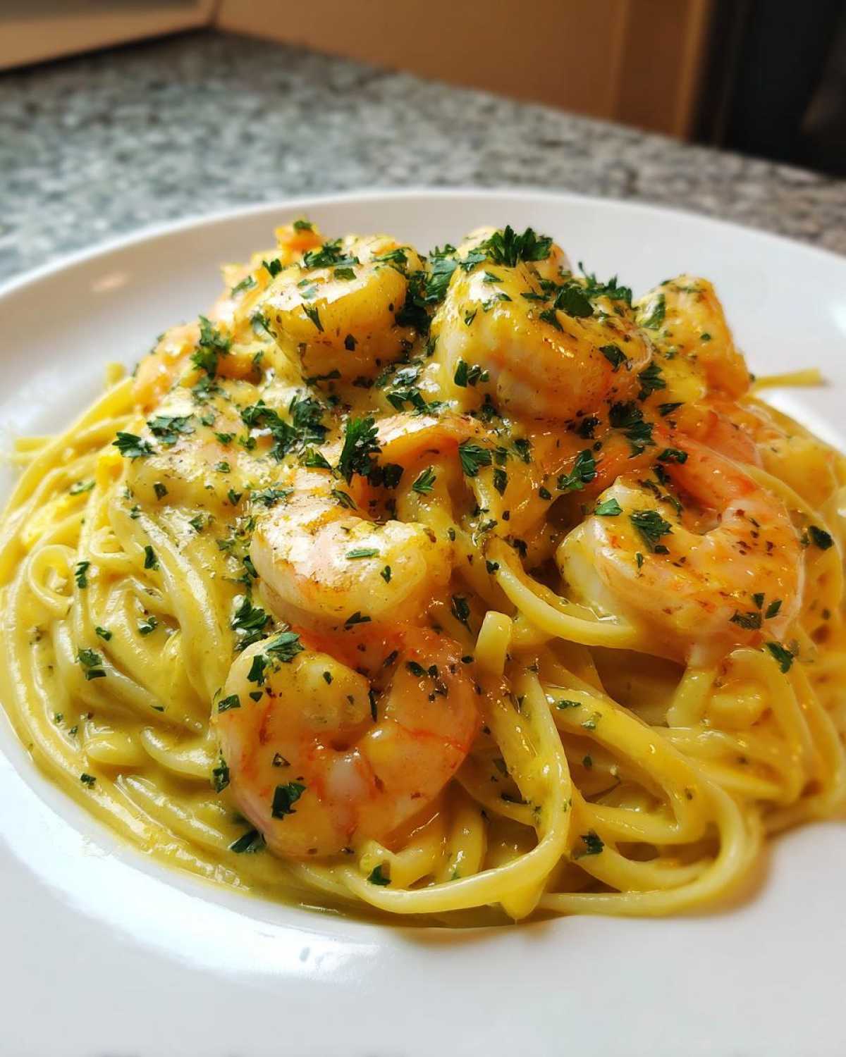 Close-up of a plate piled high with Creamy Lemon Shrimp Pasta with Garlic Sauce, topped with fresh parsley.
