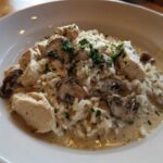 A serving of Creamy Mushroom Chicken and Rice Skillet in a white bowl, topped with parsley.