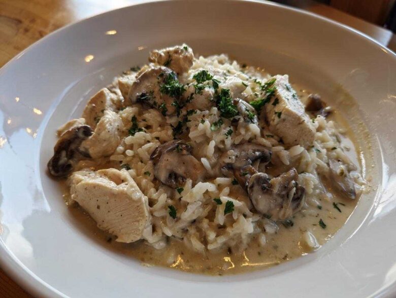A serving of Creamy Mushroom Chicken and Rice Skillet in a white bowl, topped with parsley.