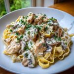 A close-up of rich Creamy Mushroom Chicken Pasta with garlic sauce, topped with fresh parsley.