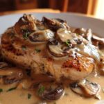 A perfectly seared chicken breast smothered in a rich, creamy mushroom sauce and garnished with parsley.