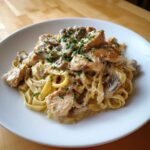 A close-up of Creamy Mushroom Garlic Pasta with Chicken served on a white plate, topped with parsley.
