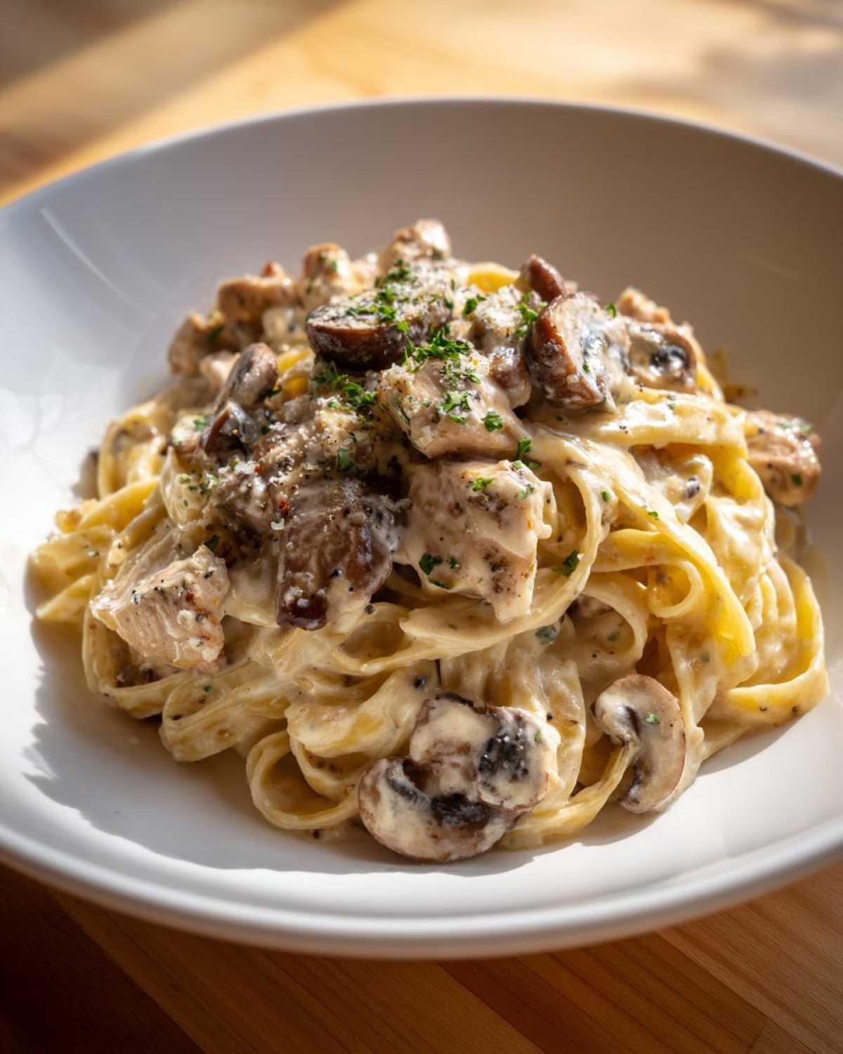 A close-up of rich Creamy Mushroom Garlic Pasta with Chicken, topped with parsley and Parmesan cheese.