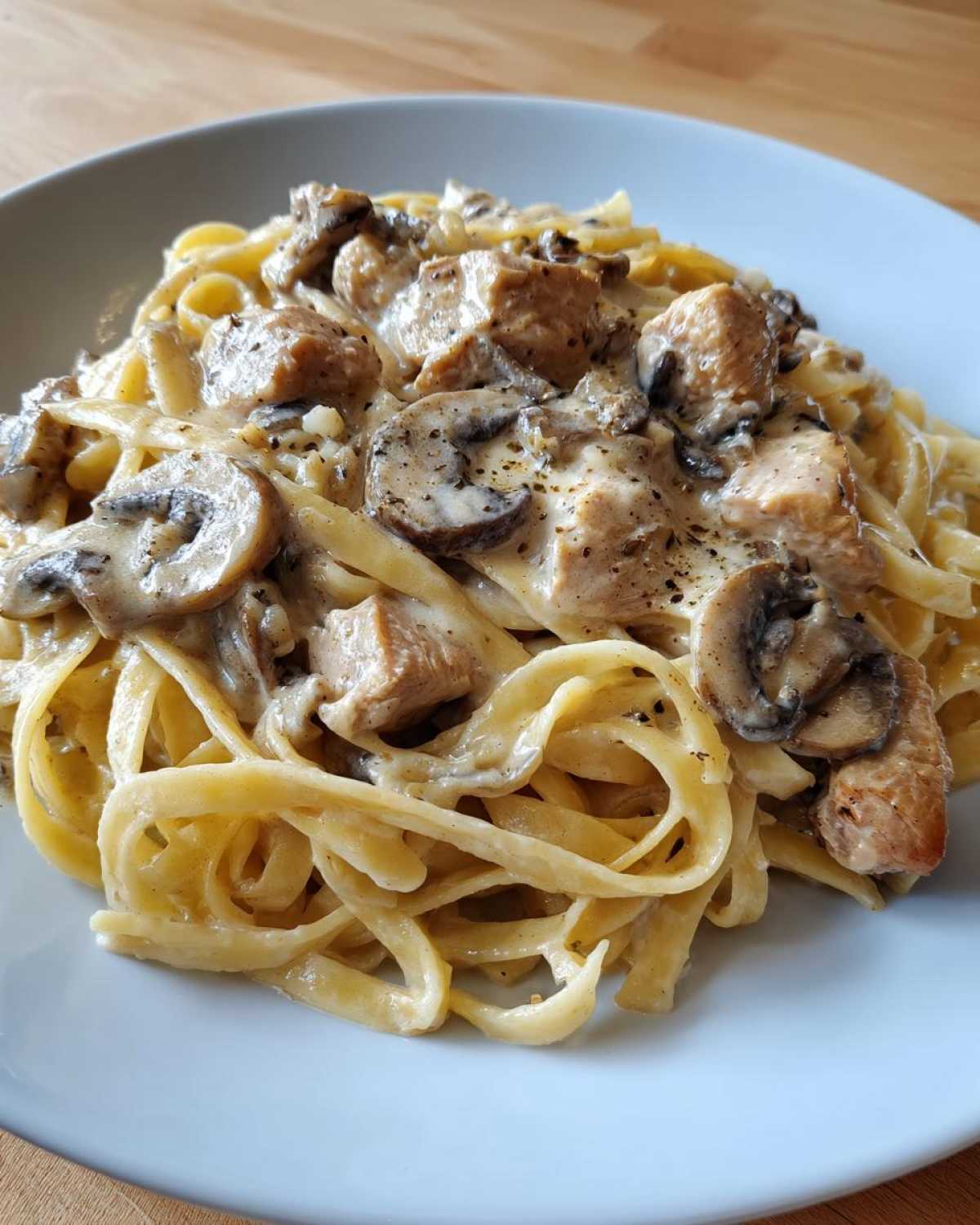 Close-up of fettuccine pasta tossed in a creamy sauce with sliced mushrooms and chunks of chicken, representing Creamy Mushroom Garlic Pasta with Chicken.