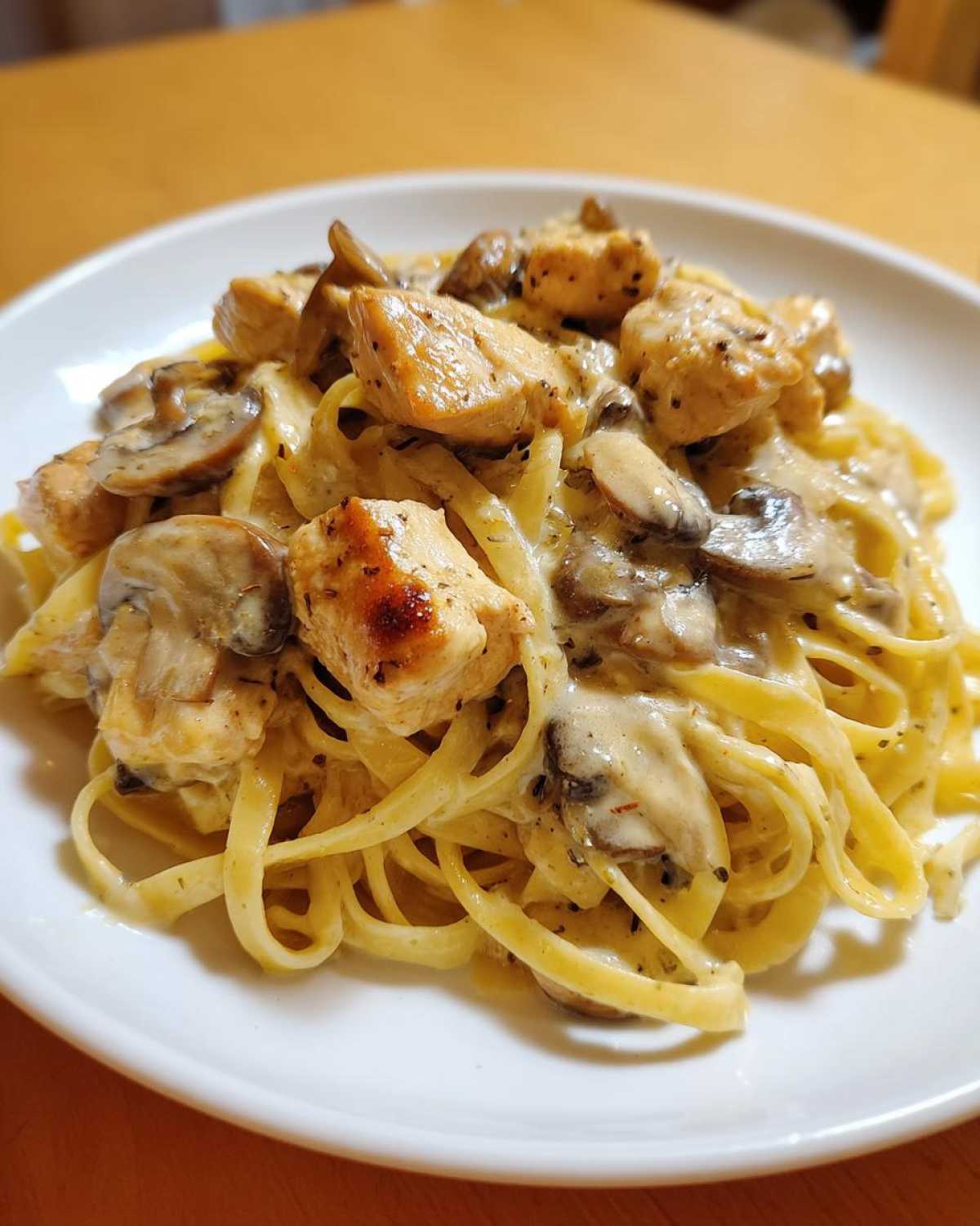 Close-up of a serving of Creamy Mushroom Garlic Pasta with Chicken featuring fettuccine, browned chicken pieces, and sliced mushrooms in a rich sauce.