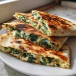 Close-up of stacked, grilled Creamy Spinach Artichoke Quesadillas oozing with melted cheese and green filling.