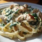 Close-up of Creamy Spinach Chicken Pasta with Alfredo Sauce featuring fettuccine, chunks of seared chicken, and wilted spinach.