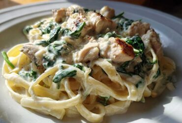 Close-up of Creamy Spinach Chicken Pasta with Alfredo Sauce featuring fettuccine, chunks of seared chicken, and wilted spinach.