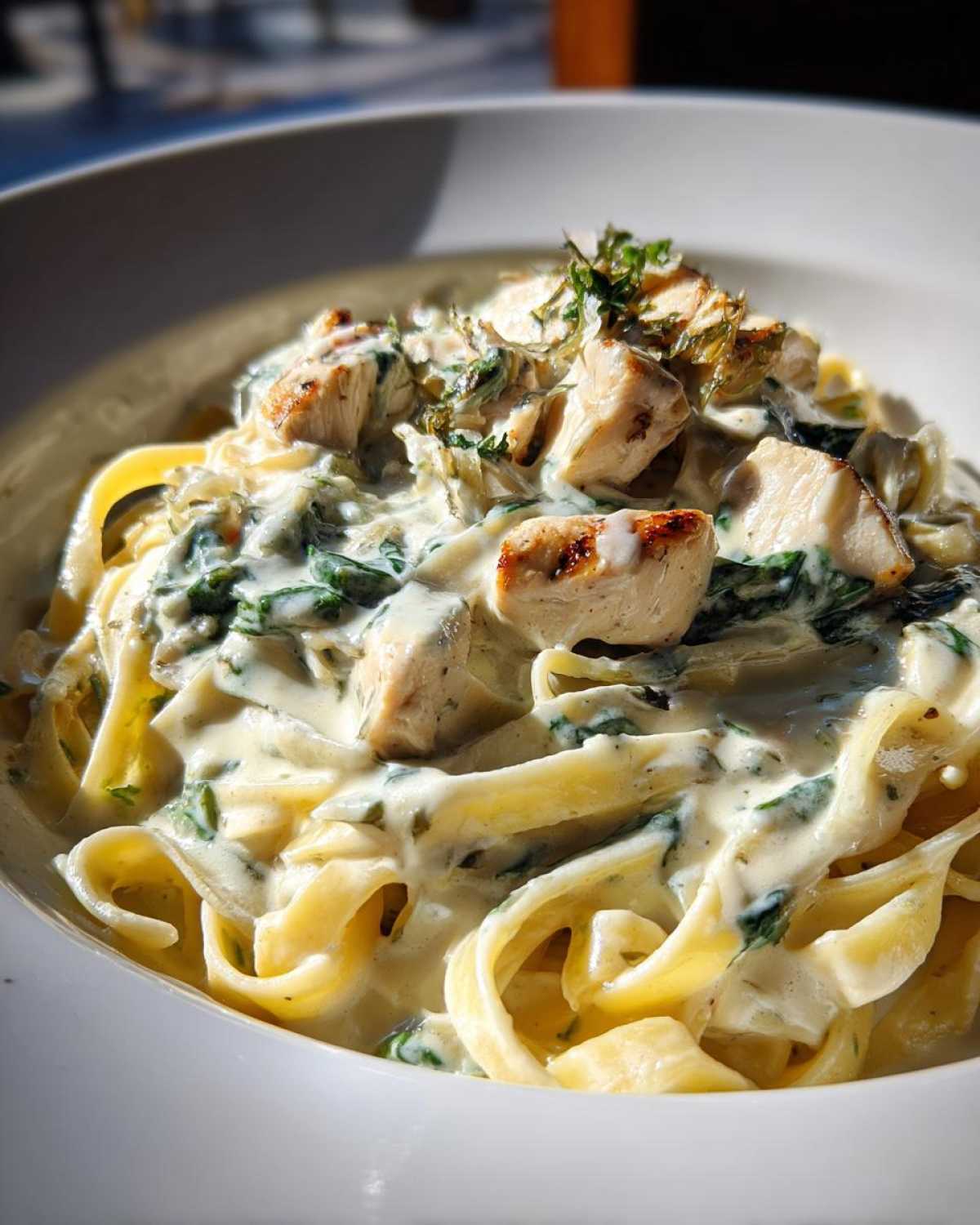 Close-up of fettuccine pasta coated in a rich, creamy spinach sauce, topped with grilled chicken pieces for Creamy Spinach Chicken Pasta.