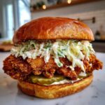 A tall, delicious Crispy Chicken Sandwich topped generously with creamy slaw and pickles.