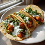Three delicious Crispy Chicken Tacos topped with creamy Garlic Lime Sauce and fresh cilantro.