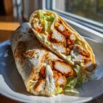 Cross-section view of a Crispy Chicken Wrap with Creamy Garlic Sauce, showing crispy chicken pieces, lettuce, and sauce.