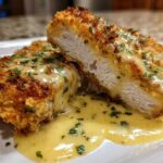 Cross-section of Crispy Parmesan Chicken Cutlets smothered in a rich, creamy sauce and topped with fresh parsley.