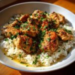 Golden brown pieces of Garlic Butter Chicken and Rice One Pot Dinner served in a white bowl and topped with fresh parsley.