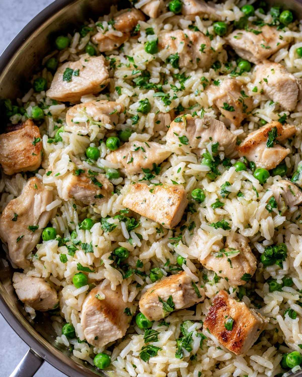 Close-up overhead view of Garlic Butter Rice with Chicken Skillet mixed with green peas and parsley.