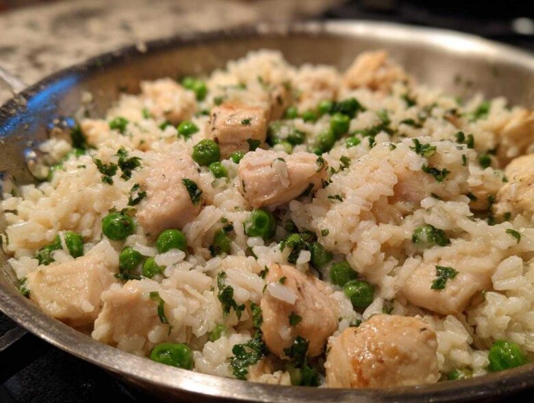Close-up of Garlic Butter Rice with Chicken Skillet, featuring white rice, cubed chicken, and green peas.