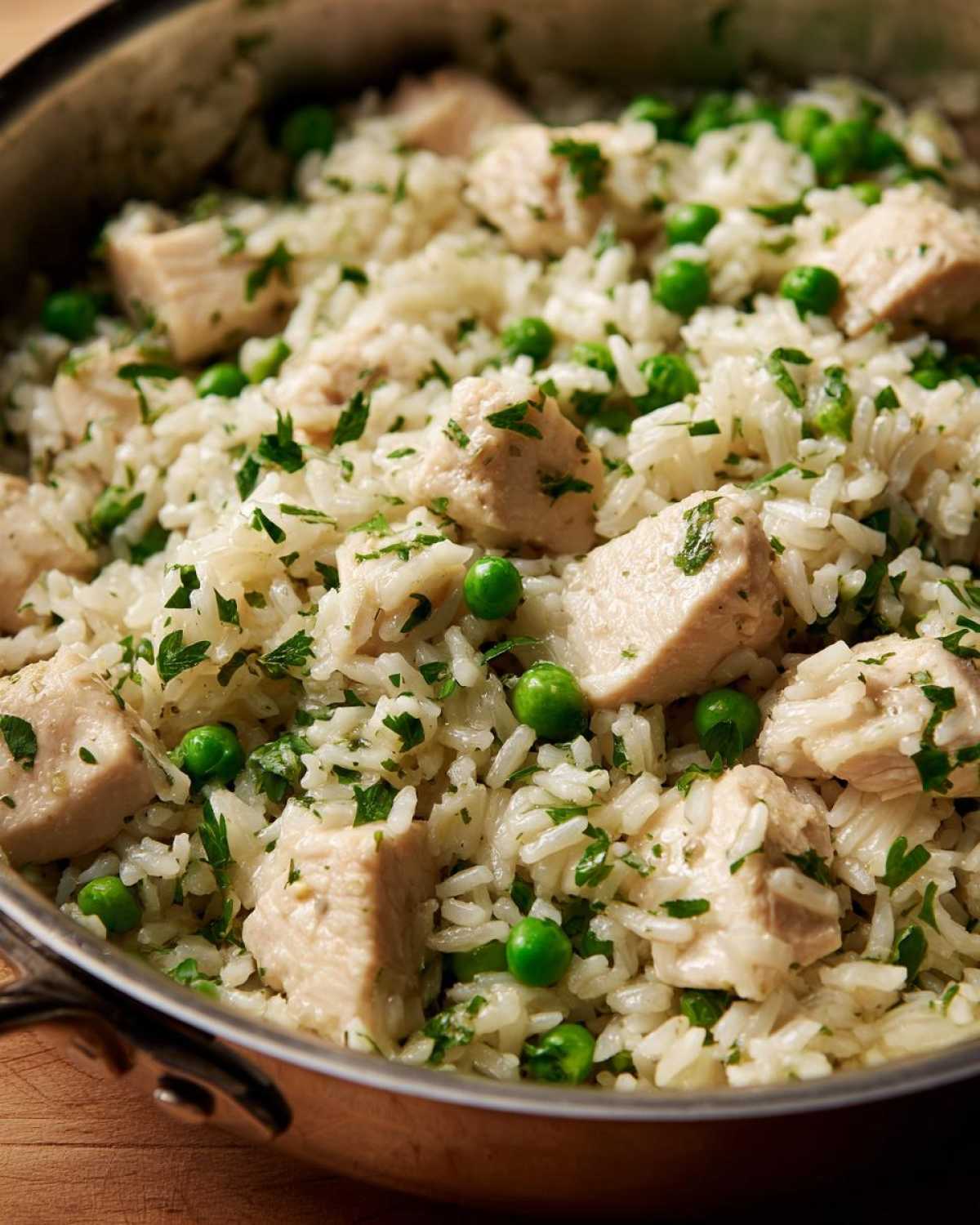 Close-up of Garlic Butter Rice with Chicken Skillet, featuring white rice, diced chicken, green peas, and parsley.
