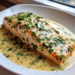 A perfectly cooked fillet of Garlic Butter Salmon with Creamy Lemon Sauce topped with fresh parsley.